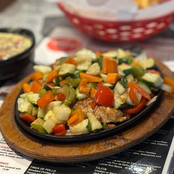 Sizzling chicken fajitas with colorful bell peppers, zucchini, and onions on a hot skillet.